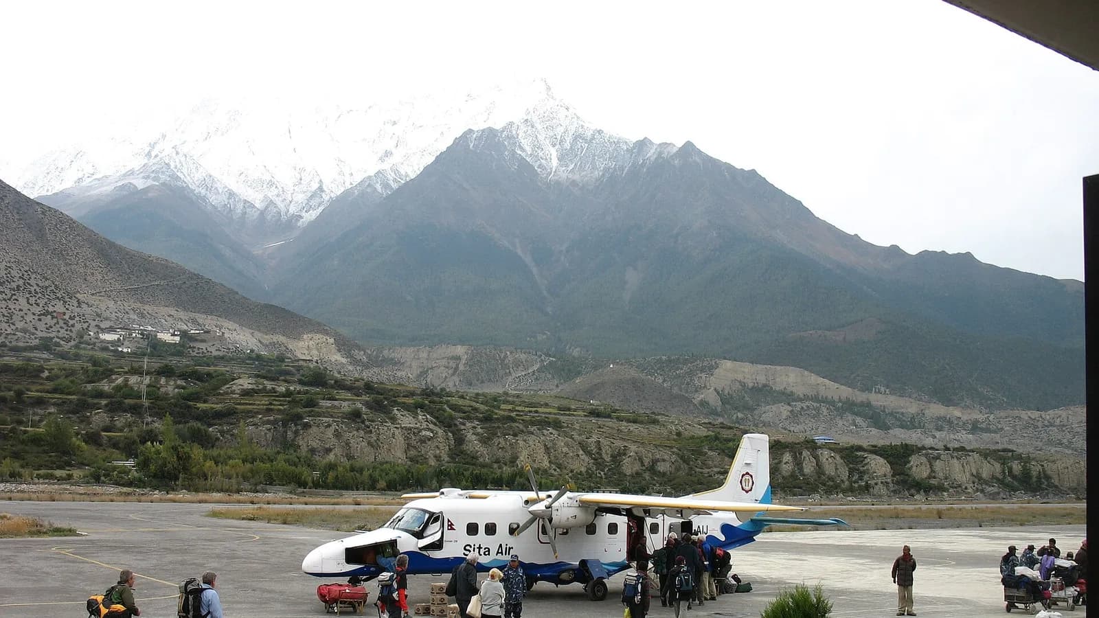 Panorama of the snow-capped Annapurna massif rising above green Himalayan foothills