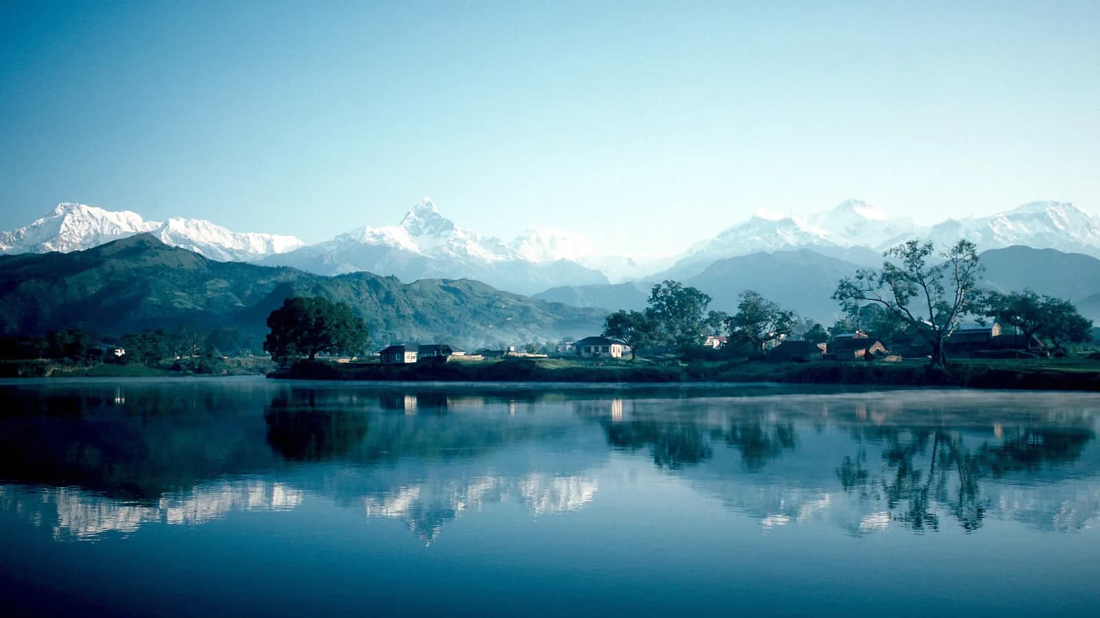 Phewa Lake in Pokhara with the Annapurna Himalaya rising behind the lakeside town at dawn