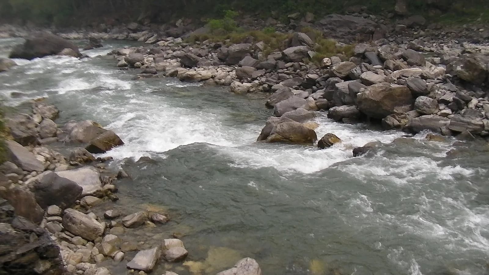 The turquoise Bhote Koshi river rushing through a steep forested Himalayan gorge near the Tibet border in Nepal