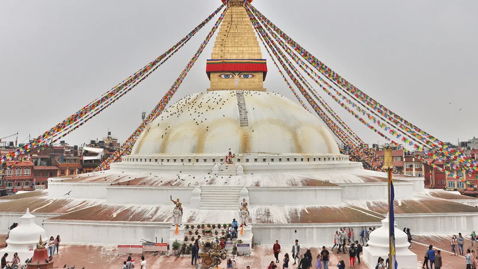 Close-up of the Buddha eyes painted on the golden tower of the Boudhanath stupa in Kathmandu, with prayer flags strung overhead.