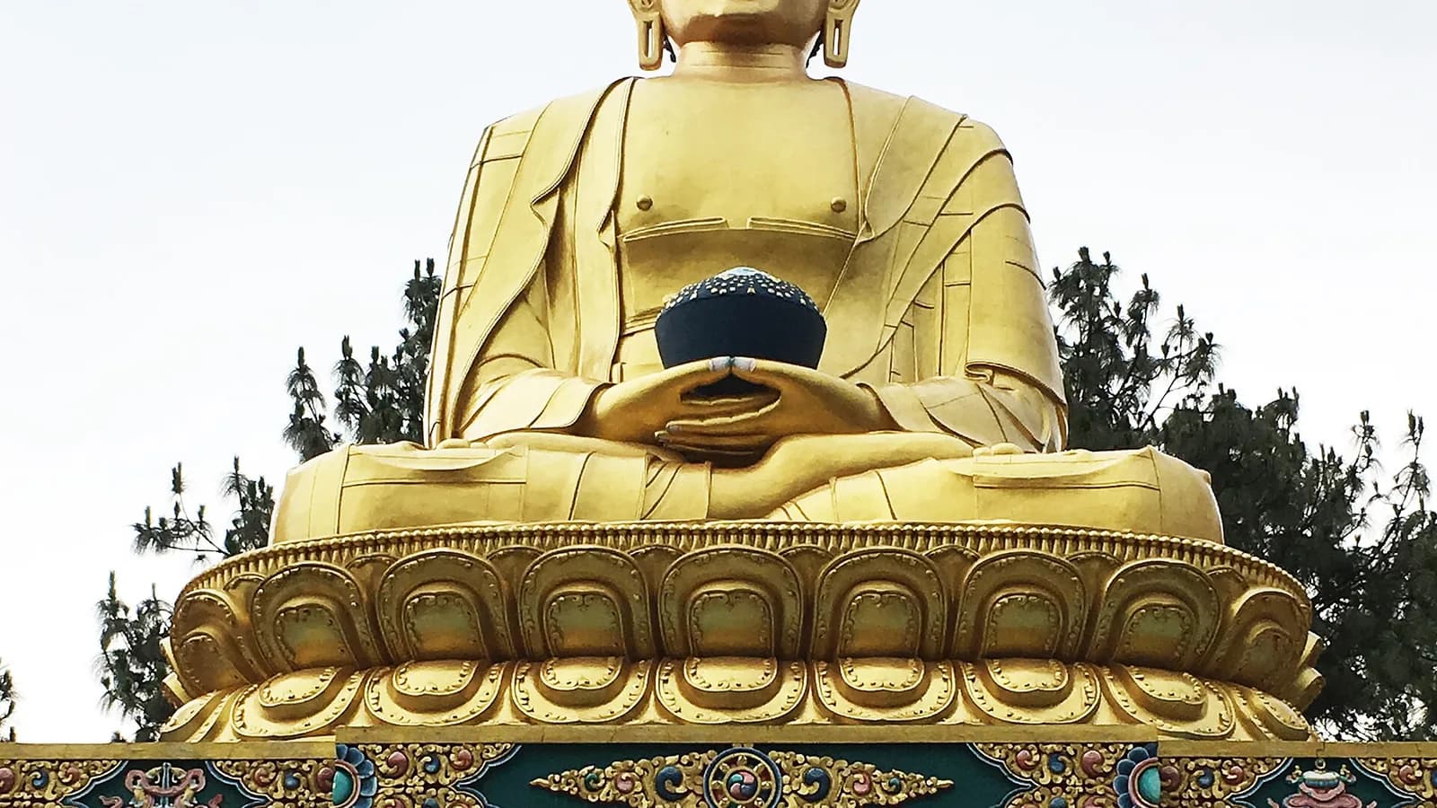 A large golden seated Buddha statue against a clear sky in the Kathmandu Valley, Nepal