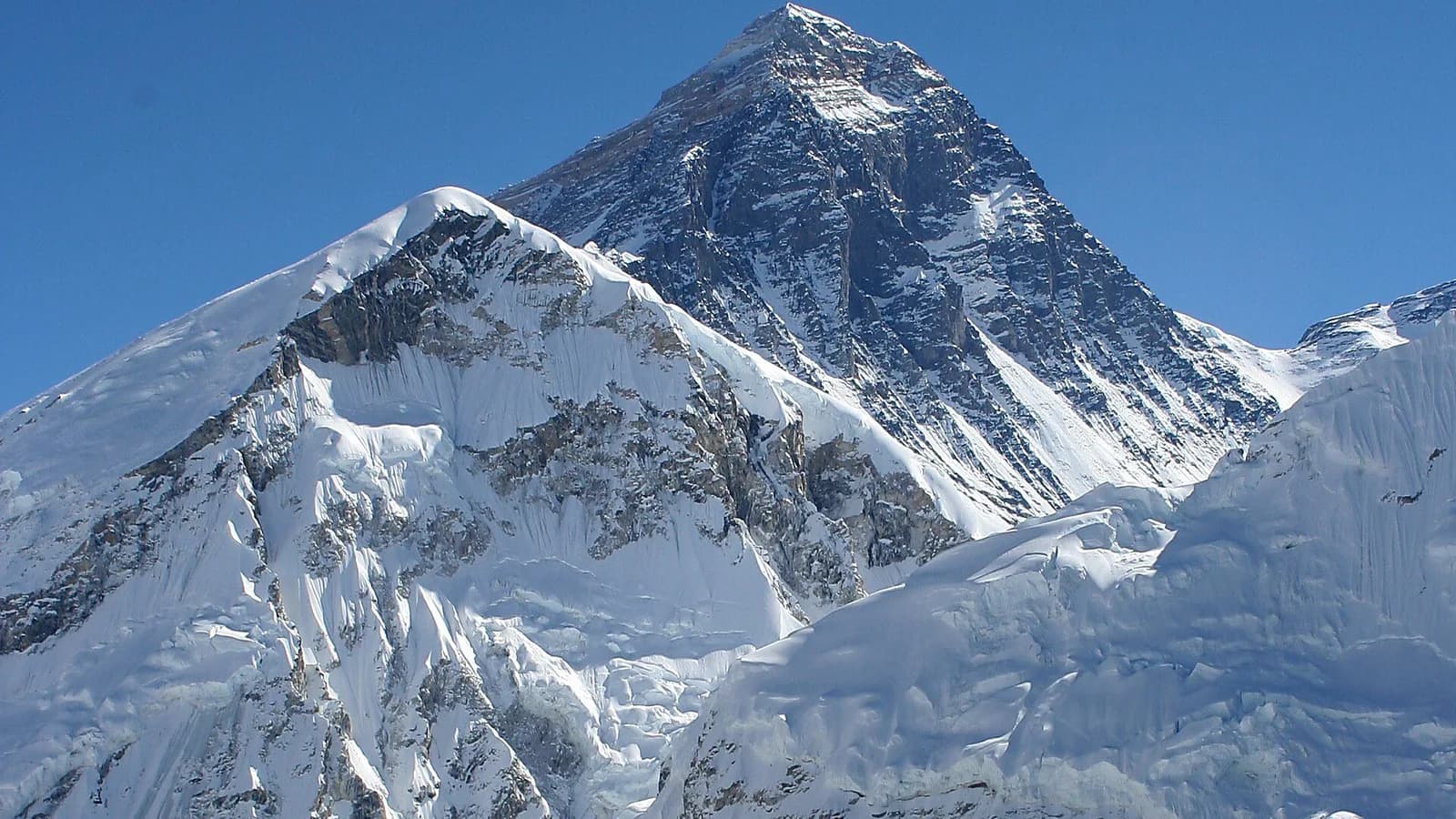 The snow-covered summit of Mount Everest rising above neighbouring Himalayan peaks under a clear sky