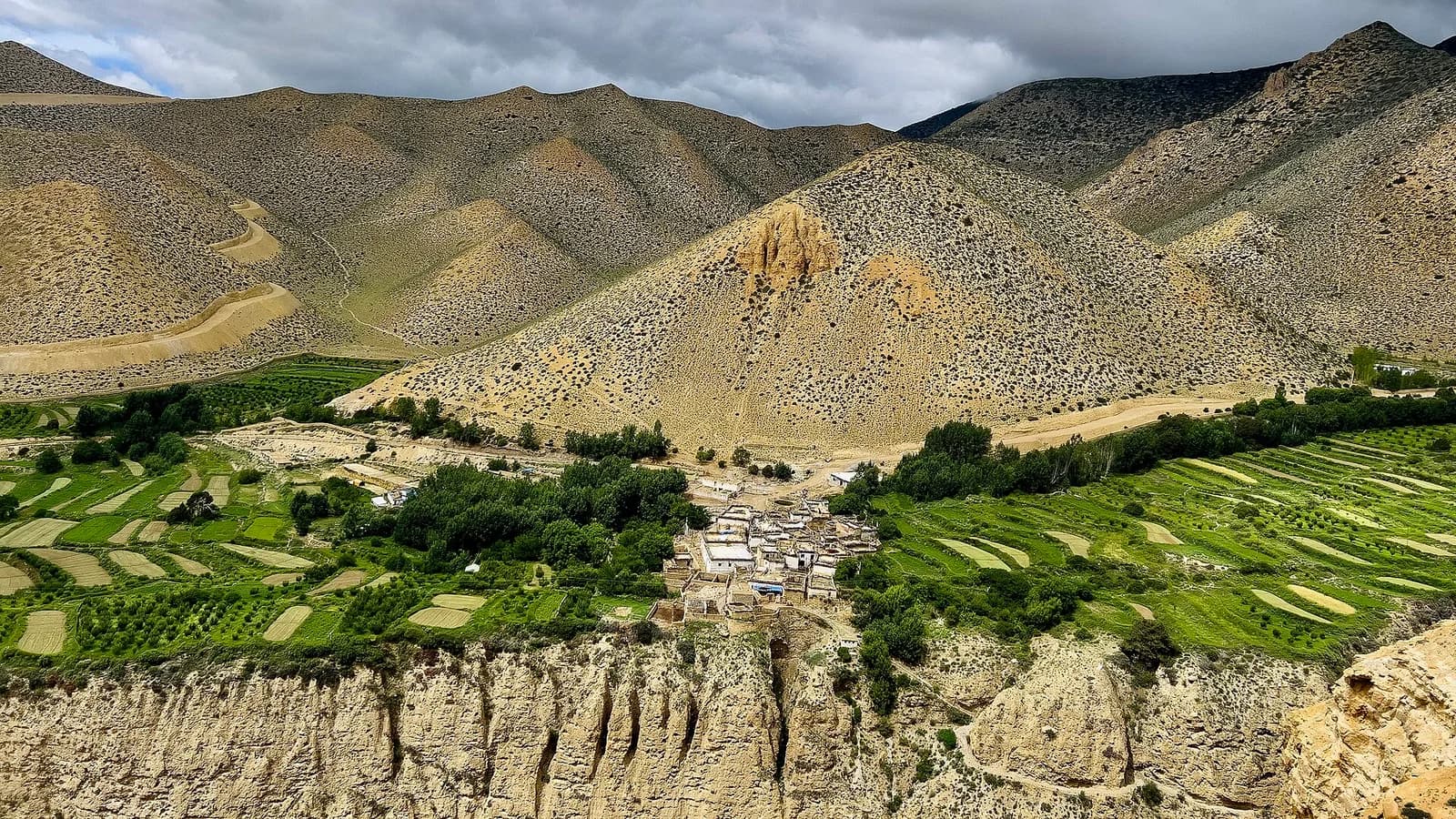 Stone and earthen village houses set among the high terraced highlands of Upper Mustang, Nepal, under a clear sky.