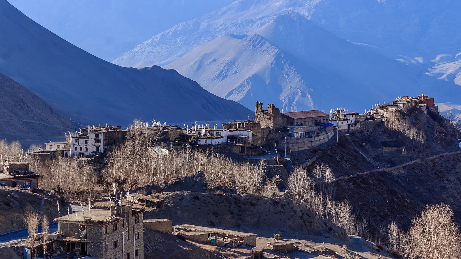 A trekker walking a stone-strewn Himalayan trail back from the Everest region under a clear sky.