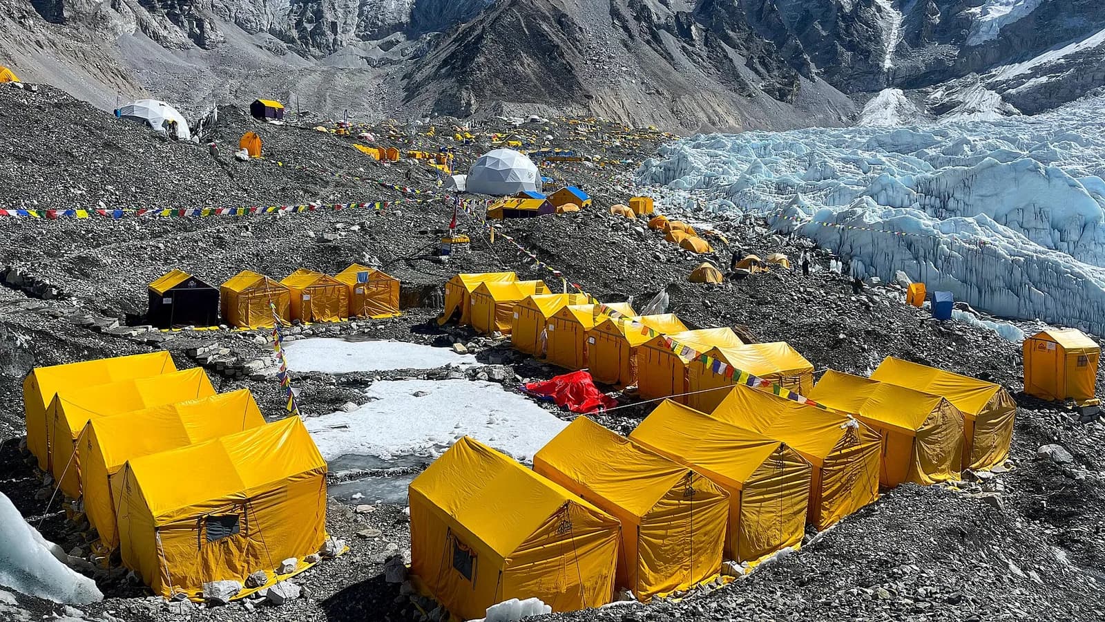 Trekkers descending a high rocky trail away from Everest Base Camp under bright Himalayan light