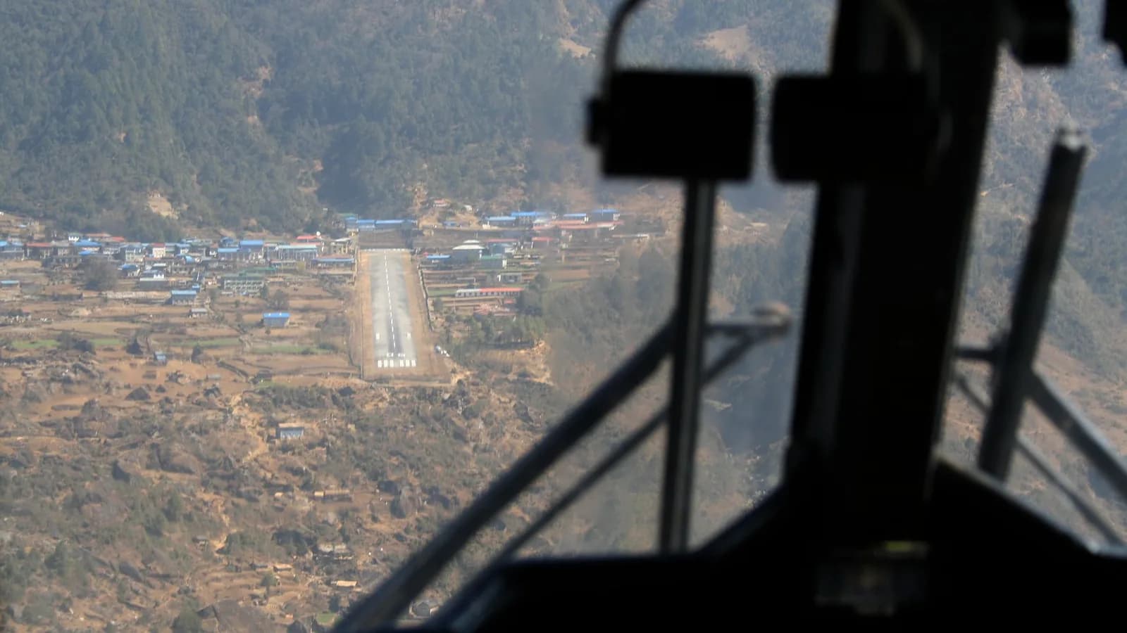 A small aircraft on final approach to Lukla's short, sloped mountain runway in the Nepal Himalaya