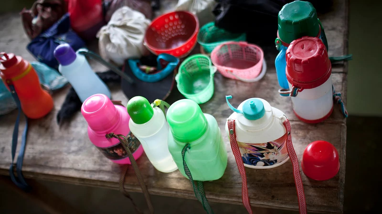 Reusable drink bottles lined up on a wooden table, the kind travelers refill with treated water