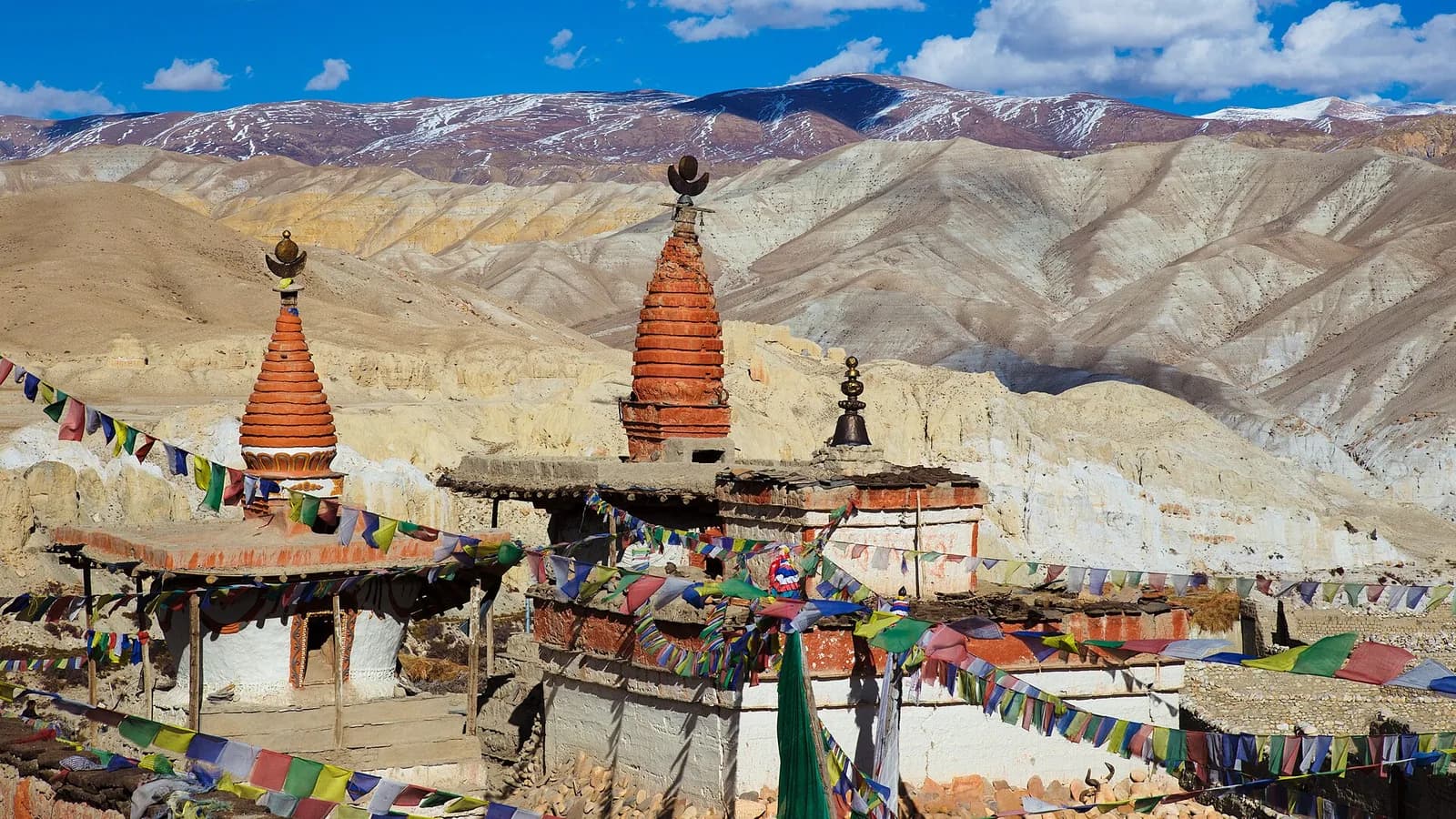 Whitewashed chortens lined up outside the mud-brick walls of Lo Manthang against the arid Upper Mustang desert