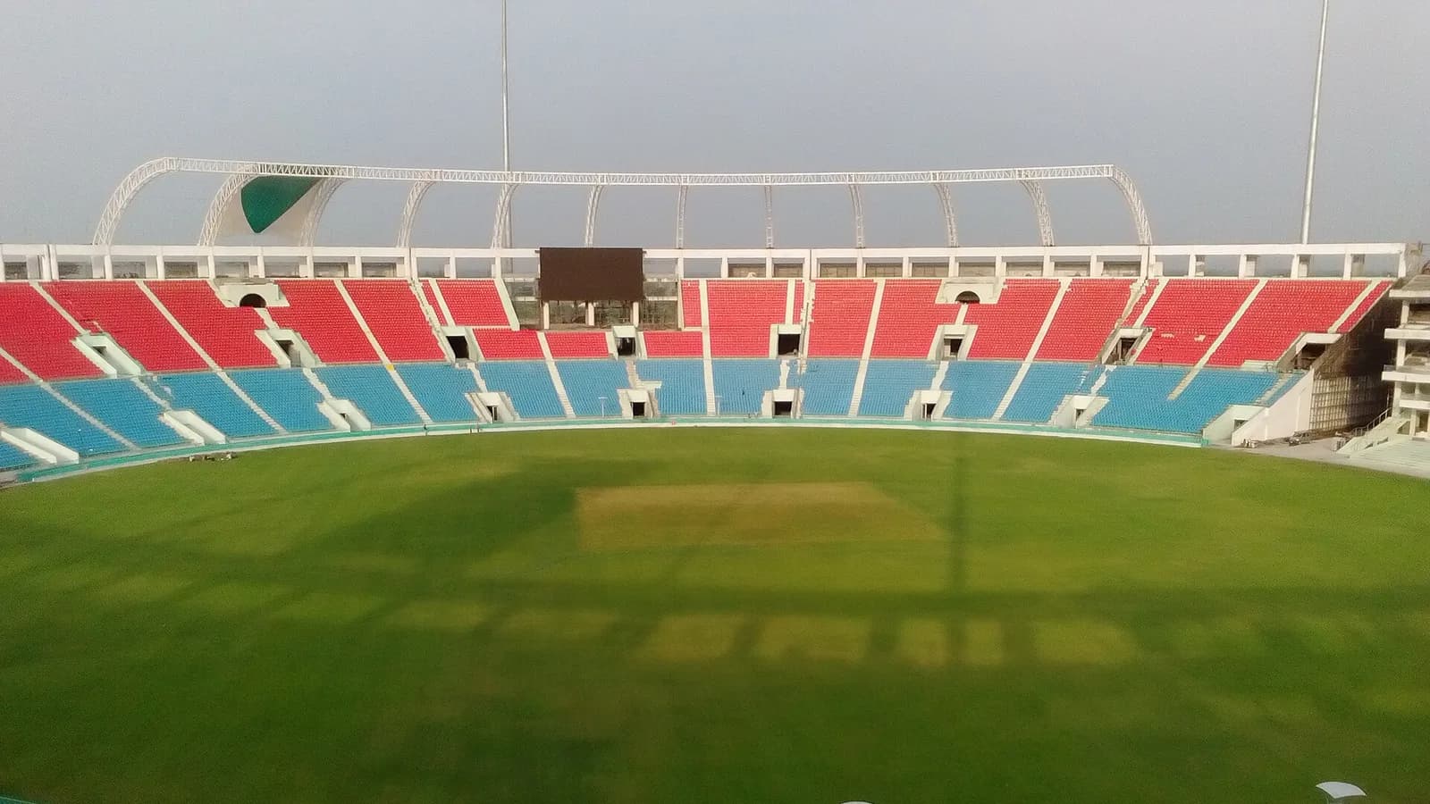 Floodlit cricket stadium with seating stands