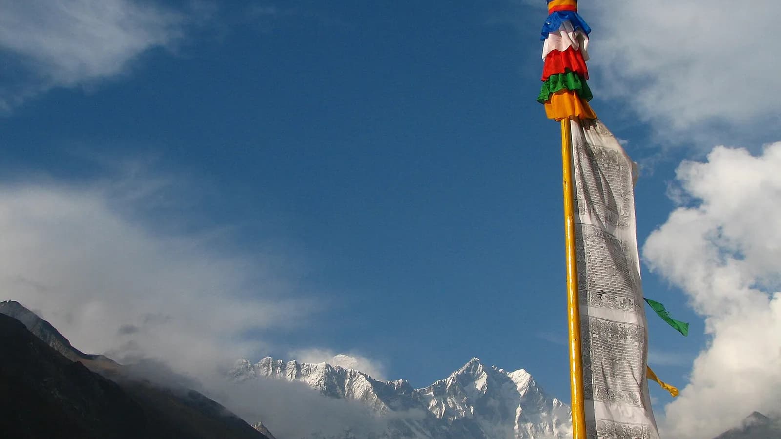 A Nepali prayer-flag pole on a ridge with the snow peaks of Lhotse and Everest behind, in the Himalaya of eastern Nepal