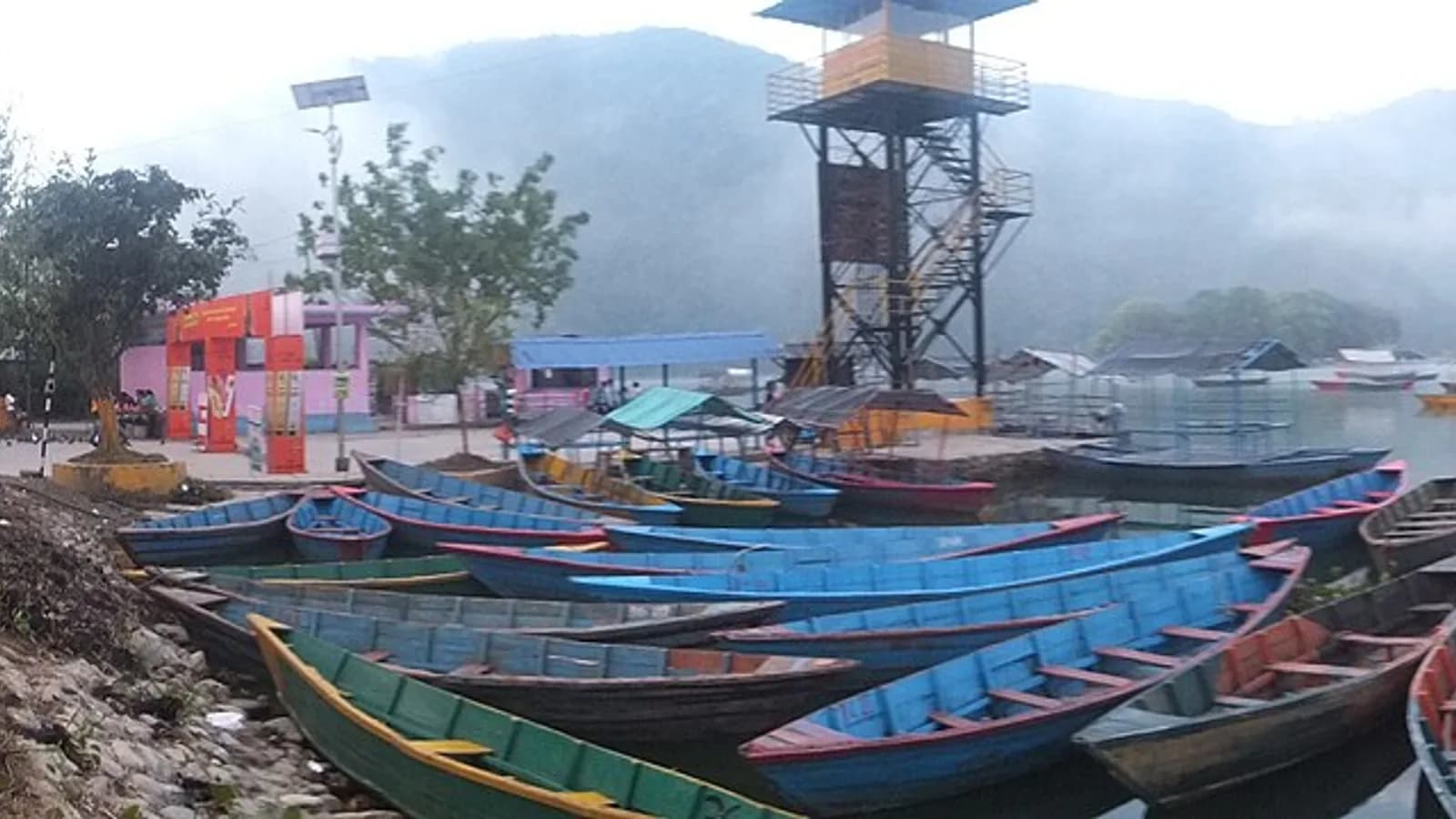 Wooden boats moored on Phewa Lake in Pokhara with green hills behind