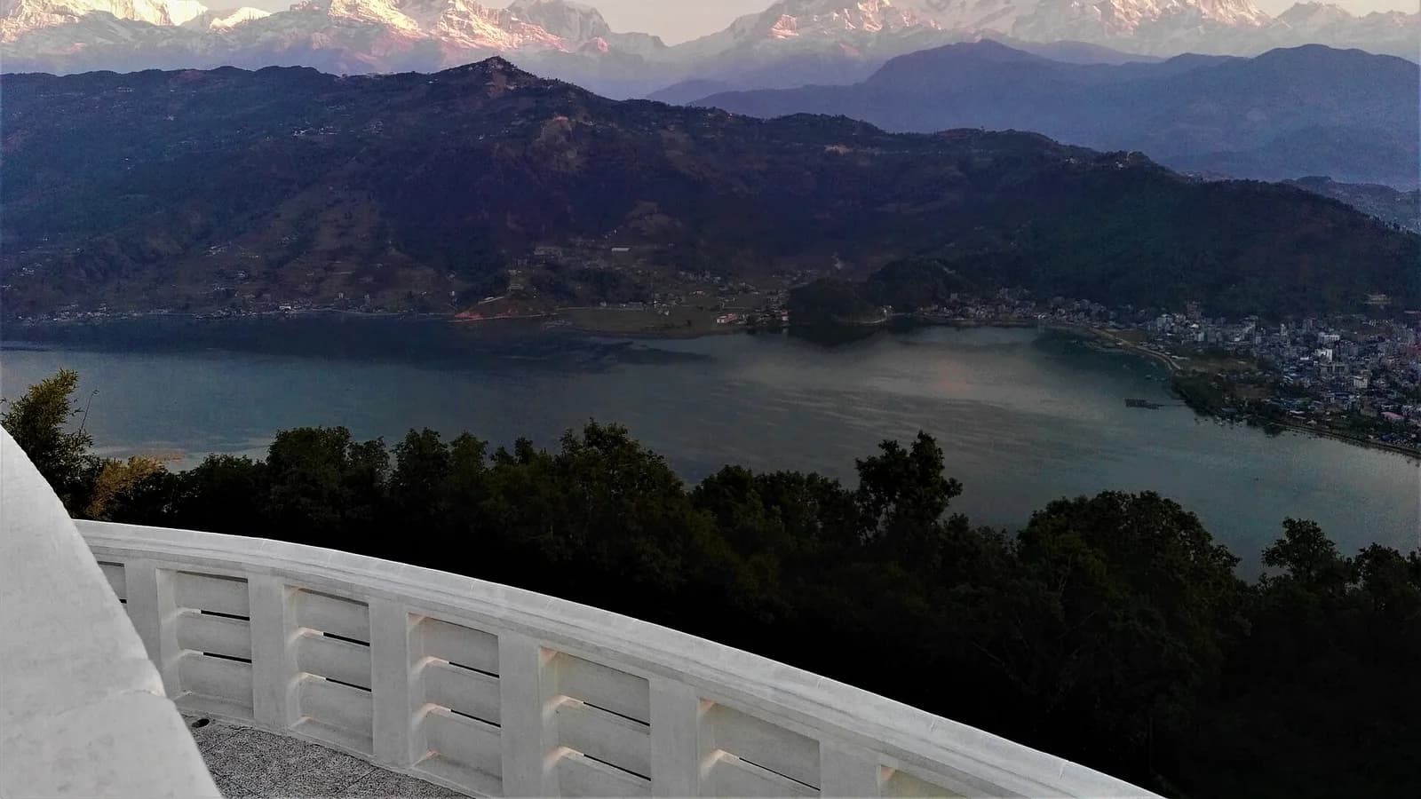 Pokhara town beside the calm waters of Phewa Lake with green hills behind