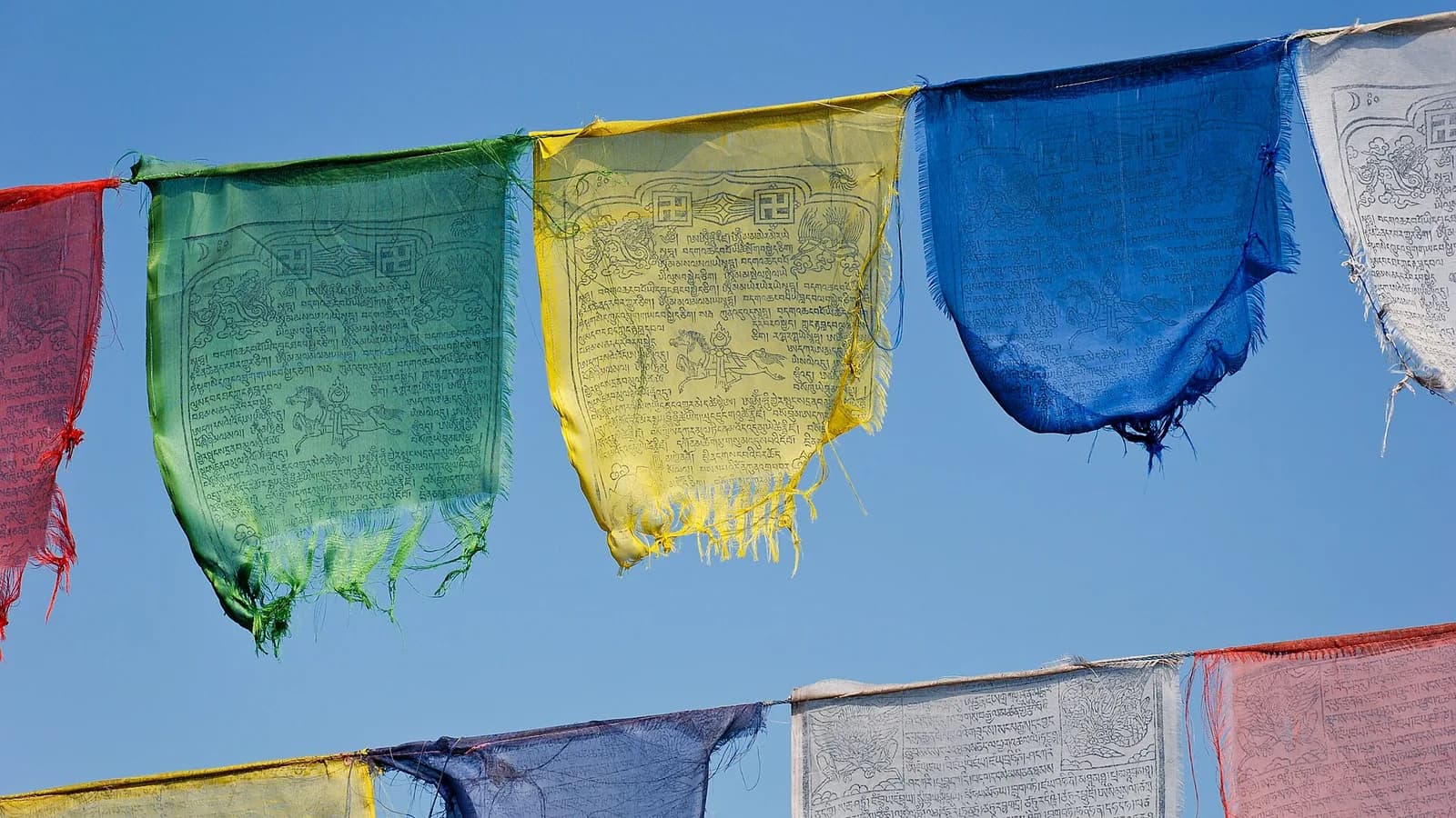 Strings of five-coloured Buddhist prayer flags strung across a Himalayan sky