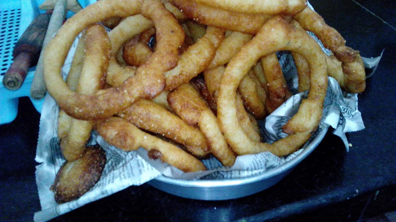 Golden ring-shaped sel roti, a Nepali sweet rice doughnut fried in oil