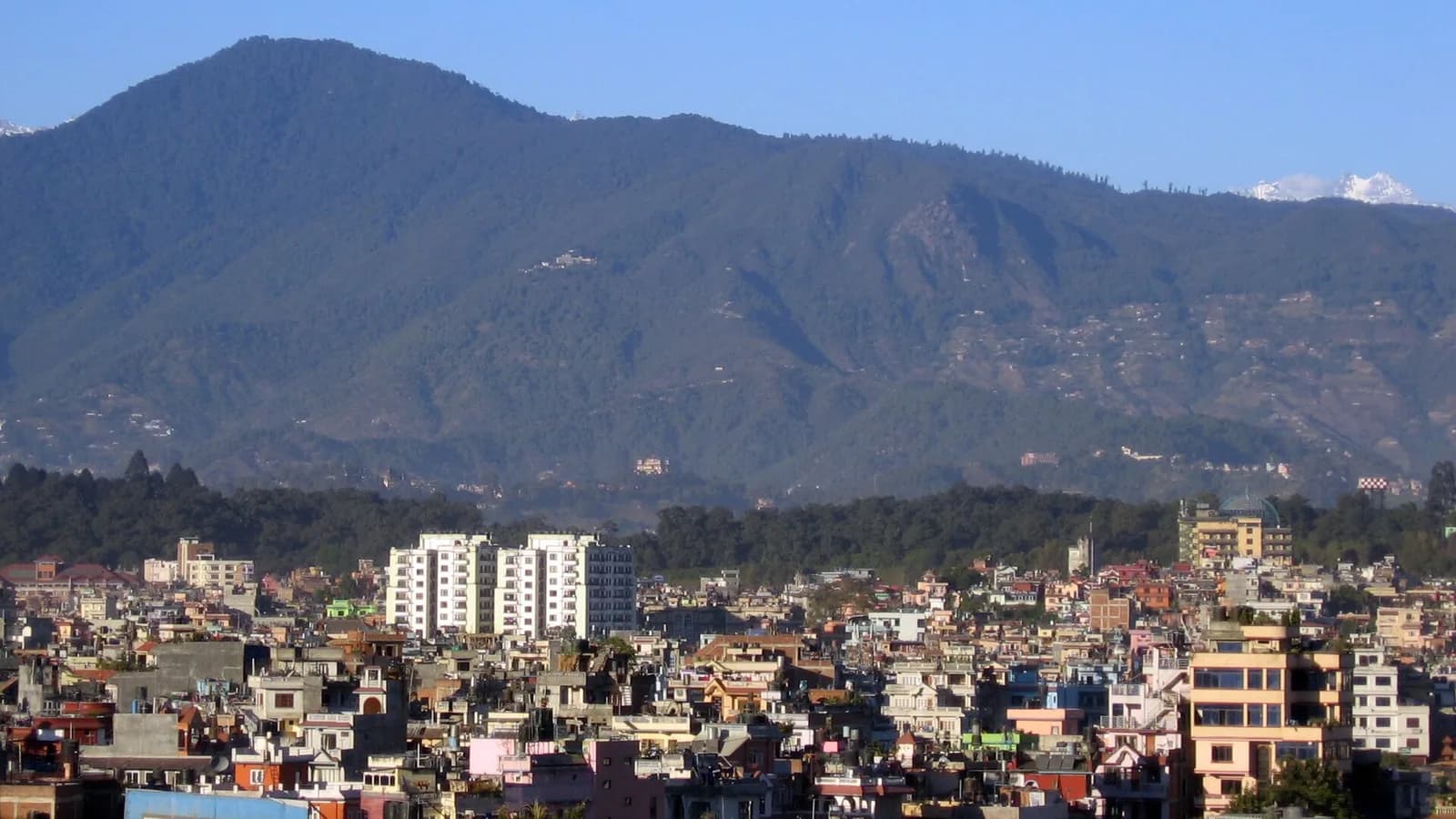The Kathmandu Valley with a forested hill rising above the city, in the foothills where Vipassana centres sit